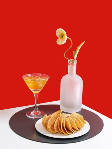 A vertical shot of appetizing snacks accompanied with drinks isolated on red background