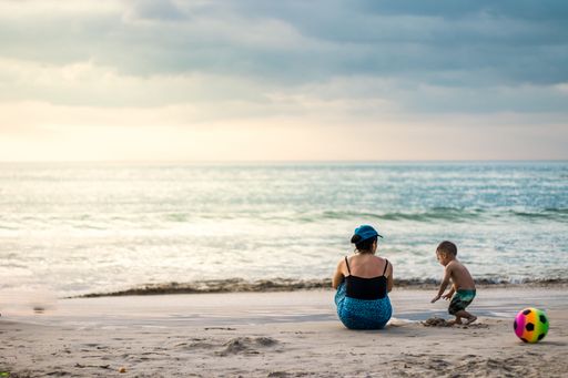 A mother and a son enjoying the weather on the sandy beach in summer