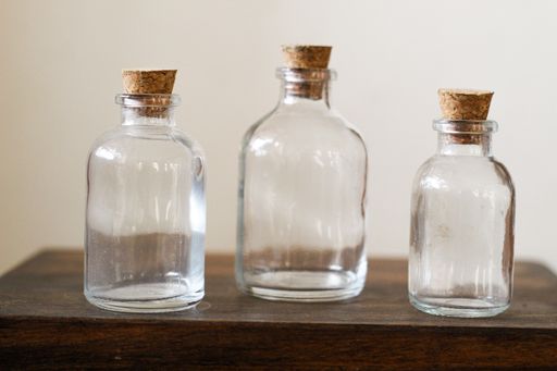 A closeup of the three  glass bottles with corks on the wooden table