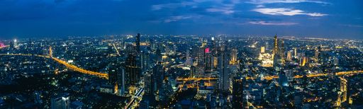An aerial view of King Power Mahanakhon skyscrapers and buildings illuminated with lights at night