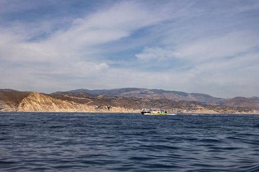 A scenic view of a boat sailing in the sea on a sunny day