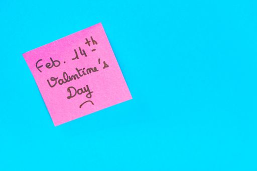 A closeup shot of a pink romantic Valentine's Day note on a blue surface