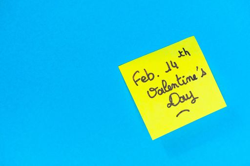 A closeup shot of a yellow romantic Valentine's Day note on a blue surface