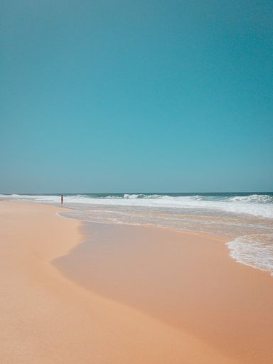 A beautiful shot of a sandy beach in rio de janeiro with strong waves of the ocean with a clear blue sky in the background