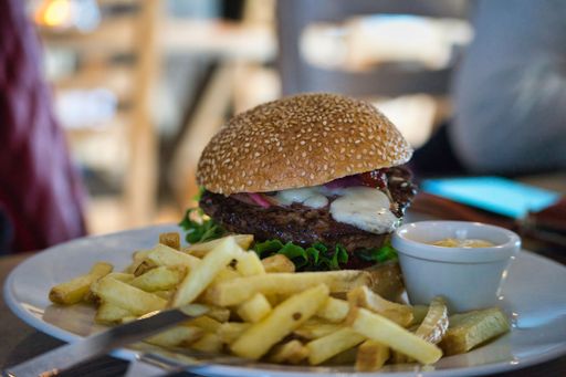 A close-up shot of a freshly prepared juicy burger and French fries drizzled with mustard sauce