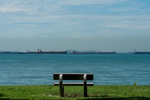 One empty bench against tropical sea and vessels, East Coast , Singapore