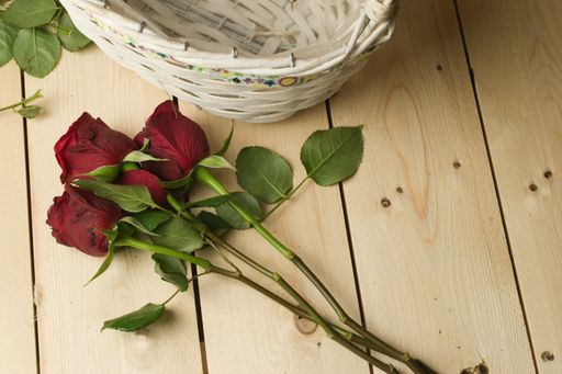 A high angle shot of a bouquet of red roses on a wooden surface