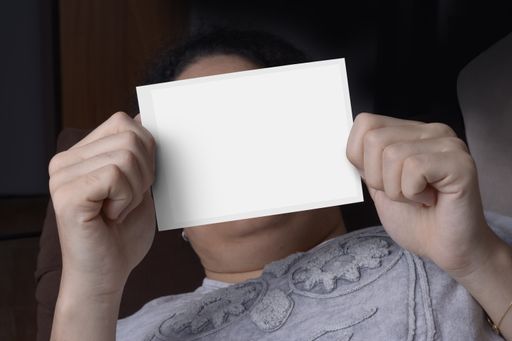 Young woman holding a blank paper in front of her face
