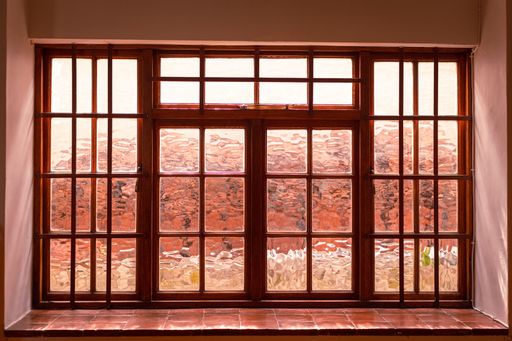 A window with a bright red tile floor beneath it, providing a vibrant contrast to the surrounding white walls