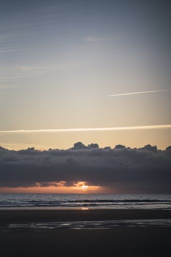 A vertical shot of a beautiful cloudscape over the shore at sunset