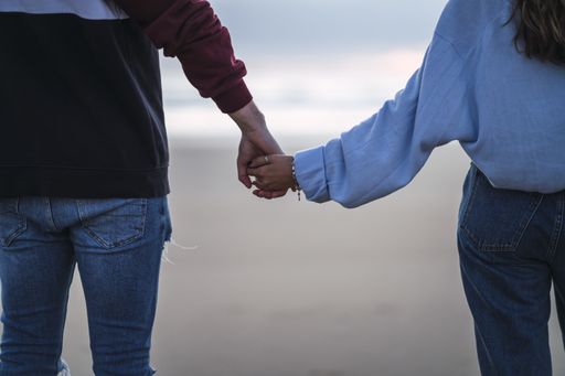 A closeup shot of a couple holding hands on the beach