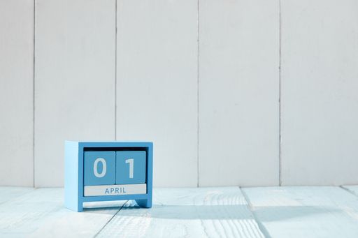 An April 1 blue cube wooden calendar on a white table - April Fools Day