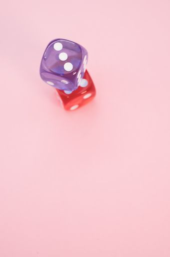 A vertical shot of purple and red dices isolated on pink background
