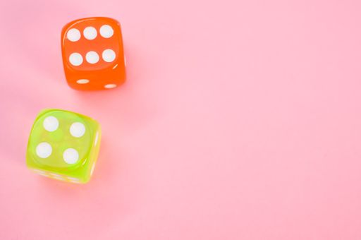 A vertical shot of orange and yellow dices isolated on pink background