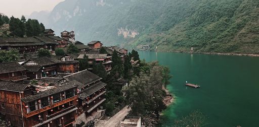 A beautiful aerial shot of a small village in China with a lake and hills on the side on a foggy day