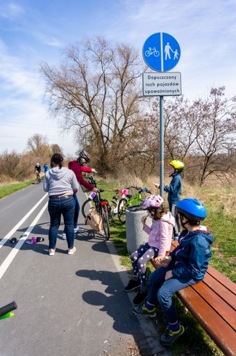 Kids and parents having a break during a bike trip on a route next to the Warta river. On of the first warm days in the spring season.