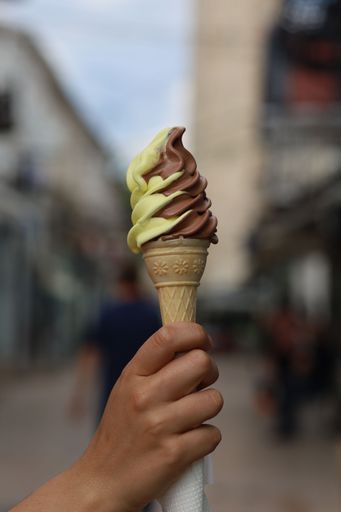 A vertical shot of a person holding an ice cream cone with chocolate and vanilla ice cream
