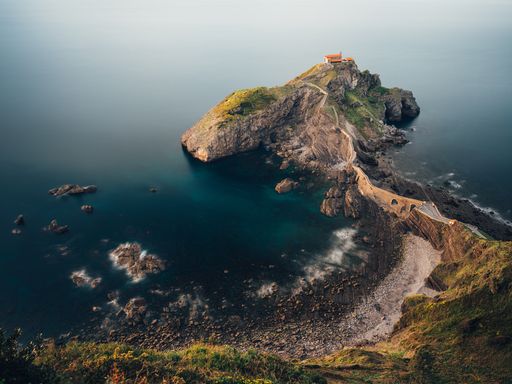 An aerial shot of a stunning San Juan de Gaztelugatxe islet during sunset on a coast of Biscay, Spain