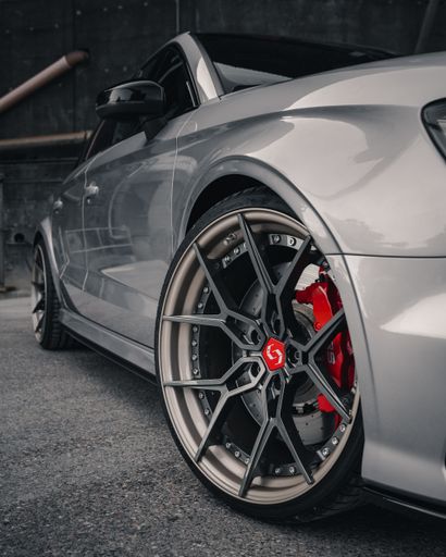 An Audi RS5 luxury car parked in front of an industrial-style building.