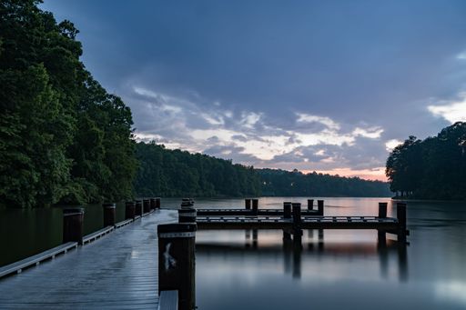 A lake surrounded by dense trees at sunset
