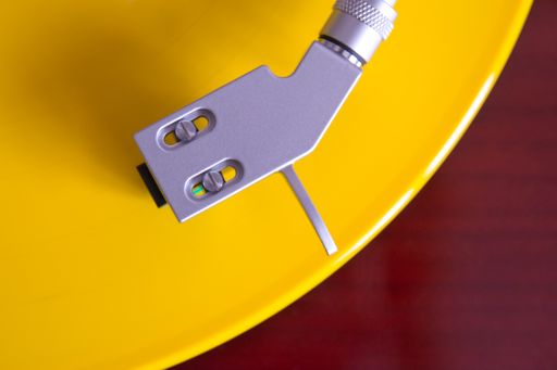 Directly above shot of turntable spinning bright yellow vinyl record. Audio equipment.