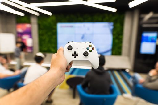 A closeup of a young adult man holding a white joystick with a blurry background