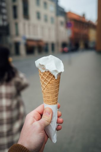 A closeup of a person holding a sweet white ice-cream cone