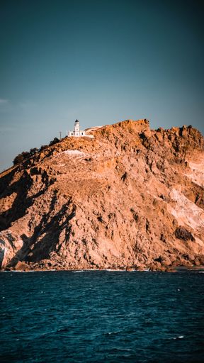 A lighthouse atop a hill on a sunny day