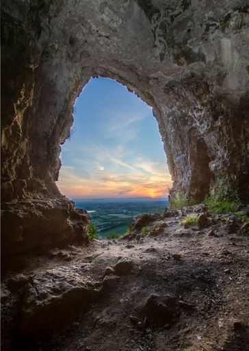 A vertical of sunset over a landscape seen from a cave