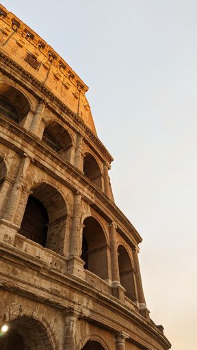 A vertical low angle shot of the Colosseum building under a clear sky