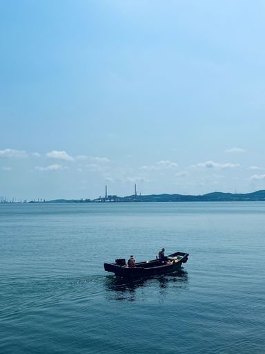 Two people in an open boat, enjoying a day out on the sun-dappled sea