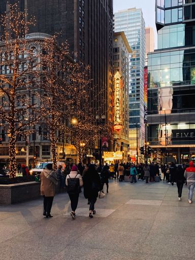 A group of people walking down a busy city street in Chicago, Illinois illuminated by the night sky