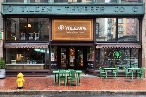 An exterior view of the cozy Yoleni's Providence cafe with green tables and chairs in the United States