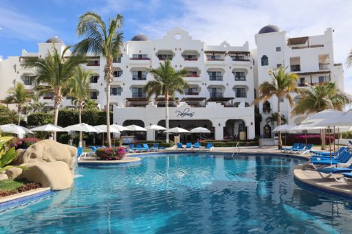 A closeup shot of pool with lounge chairs and palm trees at luxury resort in Cabo San Lucas
