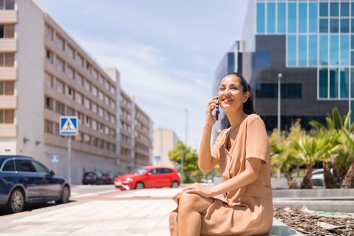 A closeup of a beautiful woman sitting while talking to cellphone on a sunny day