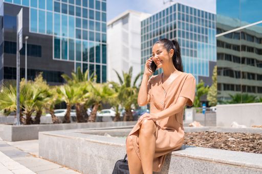 A closeup of a beautiful woman sitting while talking to cellphone on a sunny day