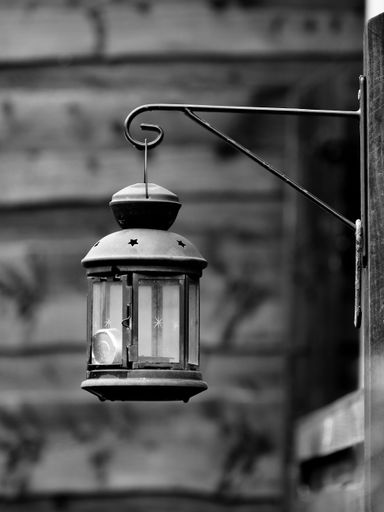 Lantern lamp hanging from a hook on the Wall monochrome image