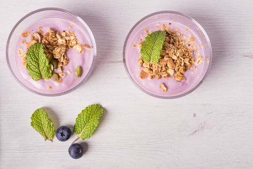 Bowls of berries yogurt with granola and oats for healthy breakfast on a rustic white table background. Top view.