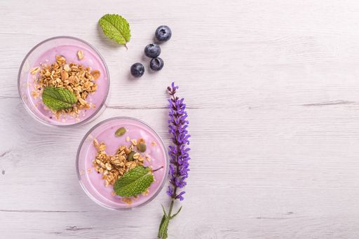 Bowls of berries yogurt with granola and oats for healthy breakfast on a rustic white table background. Top view.
