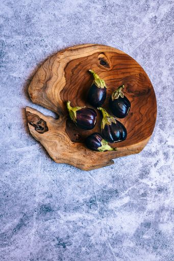 Baby Aubergines , Eggplant on Wooden Platter and Concrete Background