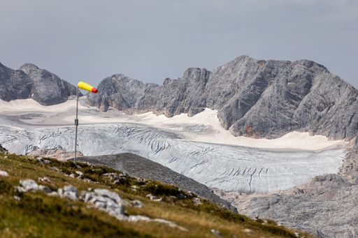 A scenic landscape of Austrian Alps featuring sprawling green meadows, snow-capped peaks, and winding rivers