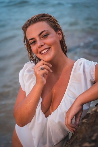 A shallow focus shot of an attractive Caucasian female in a white swimsuit posing at camera