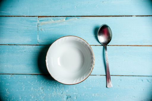 A top view of an empty bowl and a spoon on a table surface