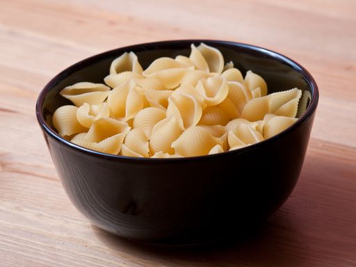 A closeup shot of uncooked pasta poured in a black bowl