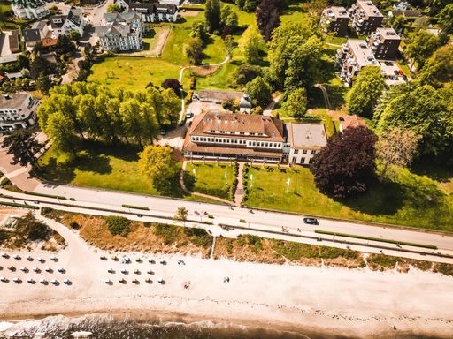 An aerial view of a hotel on a green beach against sea waves on a sunny day