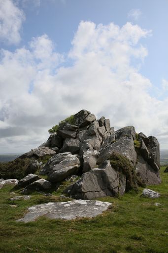 A scenic view of a hill of rocks under cloudy blue sky