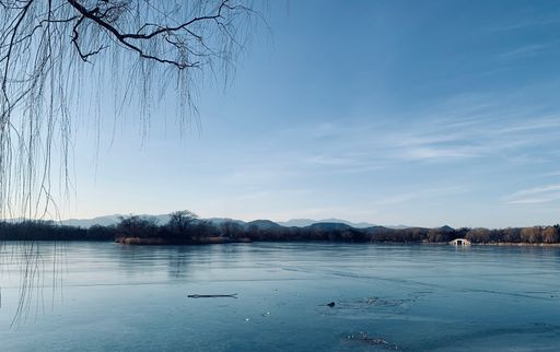 A tranquil winter scene featuring a serene frozen lake with majestic mountains in the background
