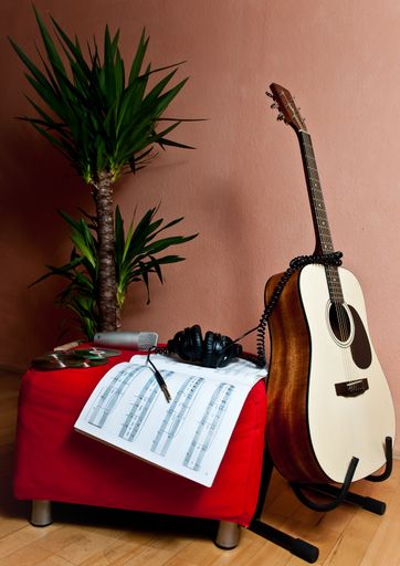 A vertical shot of musical notes next to a guitar, headphones and a plant