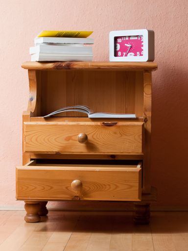 A vertical shot of a drawer with a clock and books on it