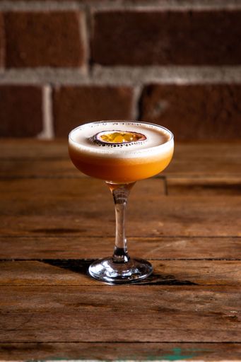 An exotic cocktail made with passion fruit, atop a wooden tabletop